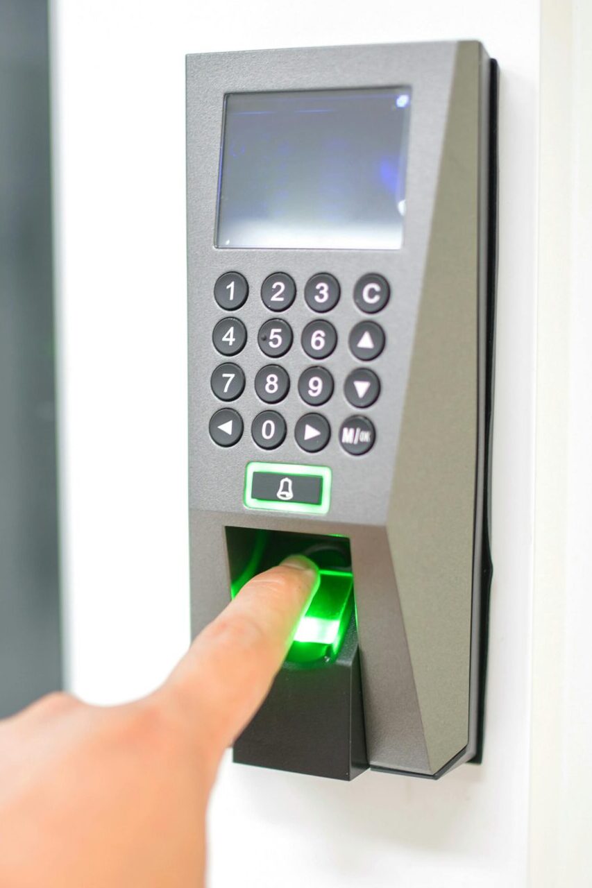 A person uses a fingerprint scanner for secure entry in a business setting.